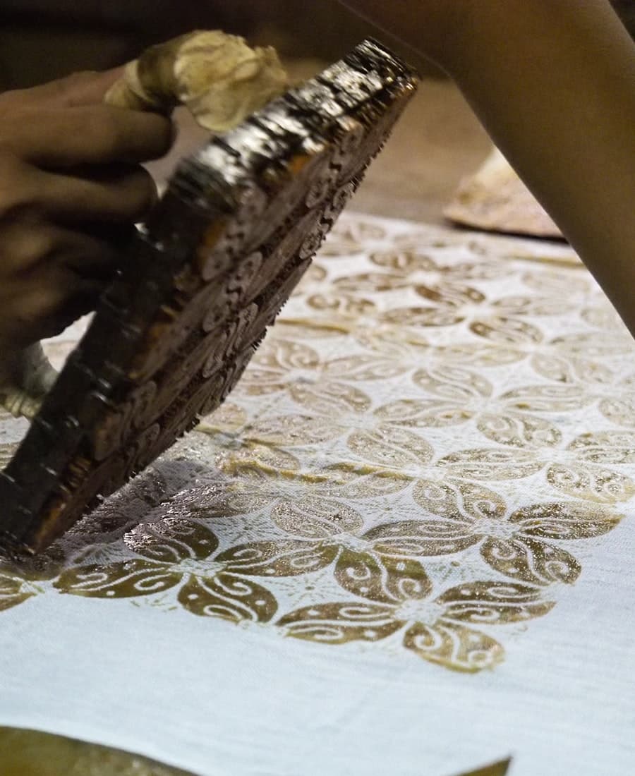Block-printing a batik pattern onto cloth by hand